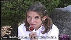 Brunette college girl in a short skirt sucks lollipop in public